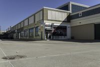 a building is in the middle of a cement parking lot, which has a large hole on the floor