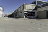 a building is in the middle of a cement parking lot, which has a large hole on the floor