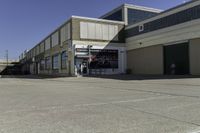 a building is in the middle of a cement parking lot, which has a large hole on the floor