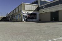 a building is in the middle of a cement parking lot, which has a large hole on the floor