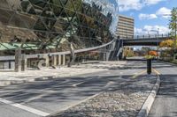 a paved street that is next to a big building with a metal sign on it