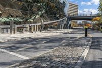 a paved street that is next to a big building with a metal sign on it