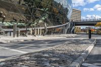 a paved street that is next to a big building with a metal sign on it