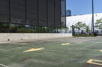 a parking lot with yellow arrows painted on it and buildings in the background there are multiple trees and grass