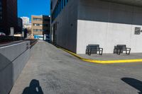 a sidewalk and benches are painted white and yellow to match the rest of a long city street