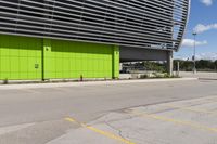 a empty parking lot that is next to a building with a green exterior and several windows