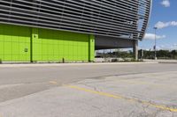 a empty parking lot that is next to a building with a green exterior and several windows