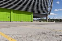 a empty parking lot that is next to a building with a green exterior and several windows