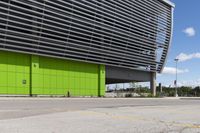 a empty parking lot that is next to a building with a green exterior and several windows