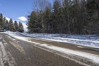 an empty road and some trees on the side of it in snow, with a white truck stuck in the middle of the snow