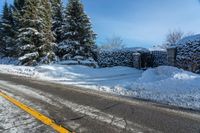 a rural road near some trees in the snow and a building on the side of it