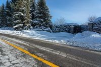 a rural road near some trees in the snow and a building on the side of it