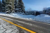 a rural road near some trees in the snow and a building on the side of it