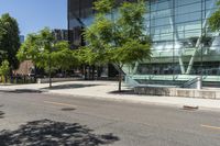 a building with glass is seen in the distance behind it is trees on both sides of a street