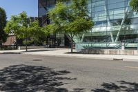 a building with glass is seen in the distance behind it is trees on both sides of a street