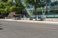 a building with glass is seen in the distance behind it is trees on both sides of a street