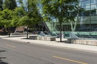 a building with glass is seen in the distance behind it is trees on both sides of a street