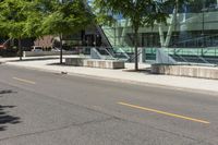 a building with glass is seen in the distance behind it is trees on both sides of a street