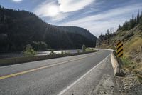 a long and winding road runs in the mountains under blue skies with bright clouds overhead