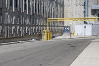 a sidewalk area with no people in it and yellow gate on the left side of the street