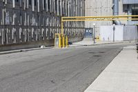 a sidewalk area with no people in it and yellow gate on the left side of the street