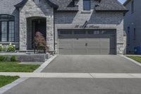 two story brick home with garage and three car garage doors and front window well maintained by large trees, flower pots, and landscaping