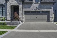 two story brick home with garage and three car garage doors and front window well maintained by large trees, flower pots, and landscaping