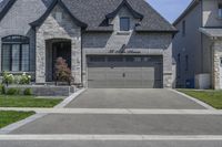 two story brick home with garage and three car garage doors and front window well maintained by large trees, flower pots, and landscaping