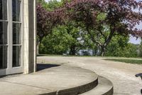 a trash can near the side of some steps by water with trees in background and buildings along the edge