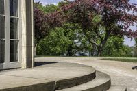 a trash can near the side of some steps by water with trees in background and buildings along the edge