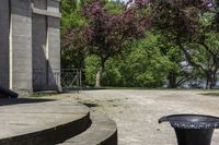 a trash can near the side of some steps by water with trees in background and buildings along the edge