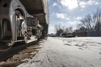 an old rail car is parked on the tracks in the snow by railroad cars with a sky background