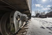 an old rail car is parked on the tracks in the snow by railroad cars with a sky background