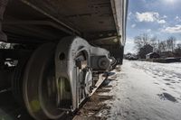 an old rail car is parked on the tracks in the snow by railroad cars with a sky background