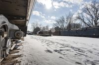 an old rail car is parked on the tracks in the snow by railroad cars with a sky background