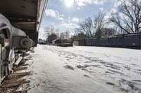 an old rail car is parked on the tracks in the snow by railroad cars with a sky background