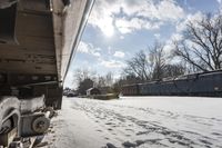 an old rail car is parked on the tracks in the snow by railroad cars with a sky background