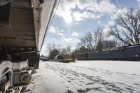 an old rail car is parked on the tracks in the snow by railroad cars with a sky background