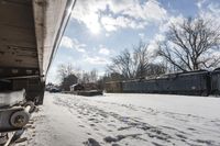 an old rail car is parked on the tracks in the snow by railroad cars with a sky background