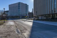 a sidewalk along the side of the road that has buildings and a sky line behind them