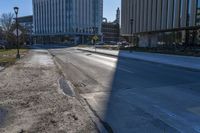 a sidewalk along the side of the road that has buildings and a sky line behind them