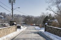 the road is lined with snow and brick along the side of a road is the bridge and a gate,