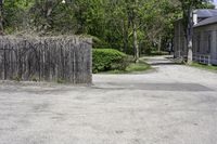 an empty parking lot with a wooden gate, benches and a small driveway leading into an old village