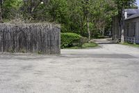 an empty parking lot with a wooden gate, benches and a small driveway leading into an old village