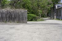 an empty parking lot with a wooden gate, benches and a small driveway leading into an old village