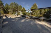 a person is walking across a bridge near a river, with the sun reflecting off of the railing