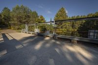 a person is walking across a bridge near a river, with the sun reflecting off of the railing