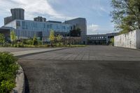 a city street surrounded by grass and tall buildings at the end of a street there is a paved pathway in front of the building