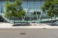 the entrance to an open office building has stairs in front of it and trees by