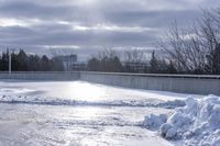 there is a large pile of snow next to a frozen road with a bridge behind it